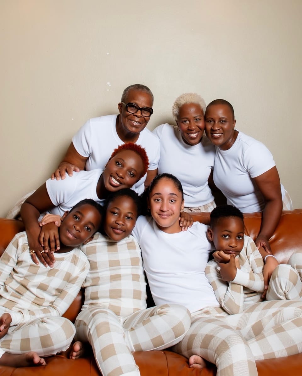 Three generations of the Booths and Such Rentals family together on a sofa, seven of them, in matching white and cream